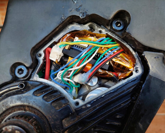 An ebike motor with the controller cover removed. A number of wires and connectors take up most of the space in the cavity.